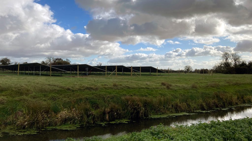 Solar panels in front of stream in field near Llanwern