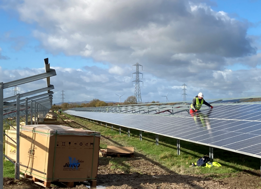 Solar panels being installed in a field near pylons